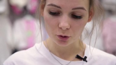 Çok güzel bir kız bir metin bir yaprak bir mağazada çocuklar için okur.