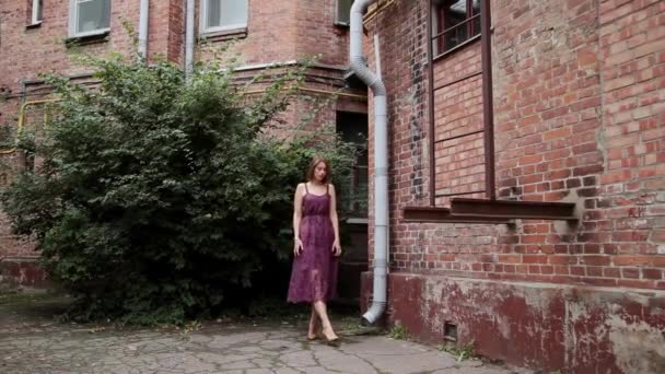 Heel mooi meisje poseren in de oude binnenplaats van bakstenen huizen. — Stockvideo