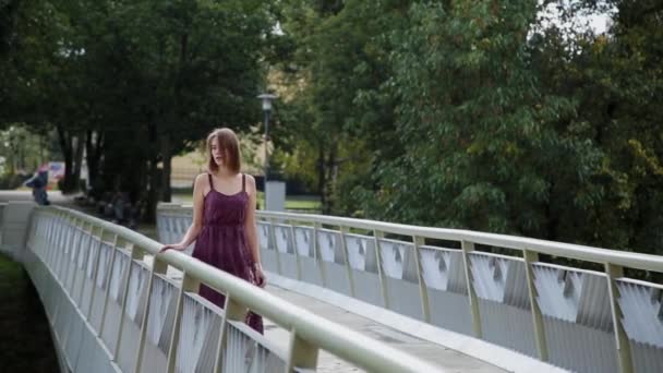 Uma menina muito bonita e sexy está de pé na ponte e olhando para a distância . — Vídeo de Stock