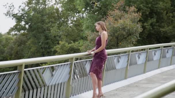 Ein sehr schönes und sexy Mädchen steht auf der Brücke und schaut in die Ferne. — Stockvideo