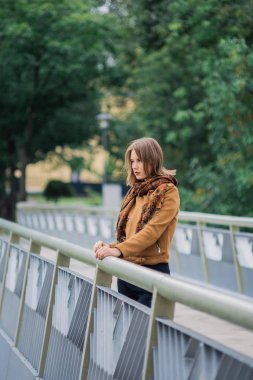 Çok güzel bir kız bir demir köprü üzerinde duruyor ve kameraya poz.