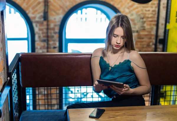 Retrato de una chica muy bonita con una tableta en un café . — Foto de Stock