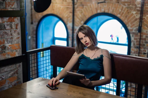 Retrato de una chica muy bonita con una tableta en un café . — Foto de Stock