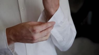 Genç Erkek Kol düğmeleri üzerinde beyaz bir gömlek koyar..