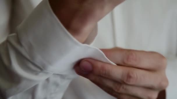 Jeune homme met des boutons de manchette sur une chemise blanche . — Video