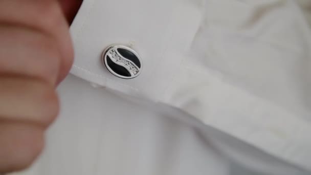 Ung man sätter manschettknappar på en vit skjorta. — Stockvideo