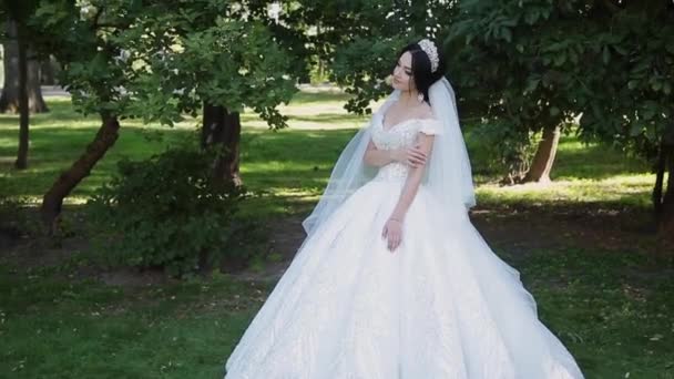 Очень красивая невеста стоит одна в парке, беспокоится, ожидая жениха — стоковое видео