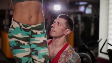 Bir eğitmen yardımıyla çubuk üzerinde bir kadın spor salonunda sıkılaştırır.