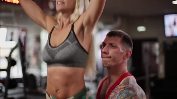 A woman in the gym tightens on the crossbar with the help of an instructor. — Stock Video