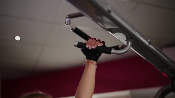 Une femme dans la salle de gym se serre sur la barre transversale . — Video