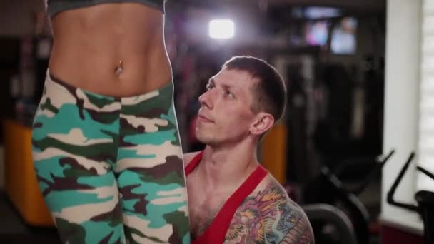 A woman in the gym tightens on the crossbar with the help of an instructor. — Stock Video