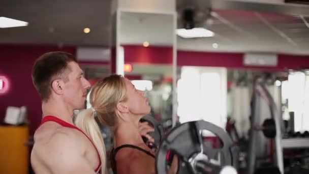 En kvinna på gymmet gör övningar med hjälp av en fitness-instruktör. — Stockvideo