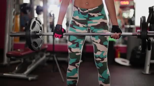 Een vrouw voert een oefening met een barbell in een fitnessclub. — Stockvideo