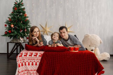 Parlak bir Noel sabahı yatakta mutlu bir aile. Yeni yıl 2019.