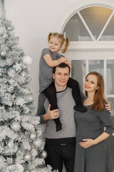Glückliche und schöne dreiköpfige Familie in einem festlichen, hellen Neujahrszimmer. — Stockfoto
