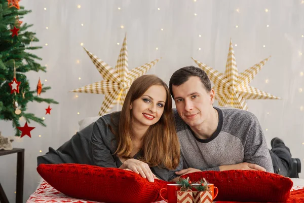 Very beautiful married couple on the bed in the New Years room. Stock Photo