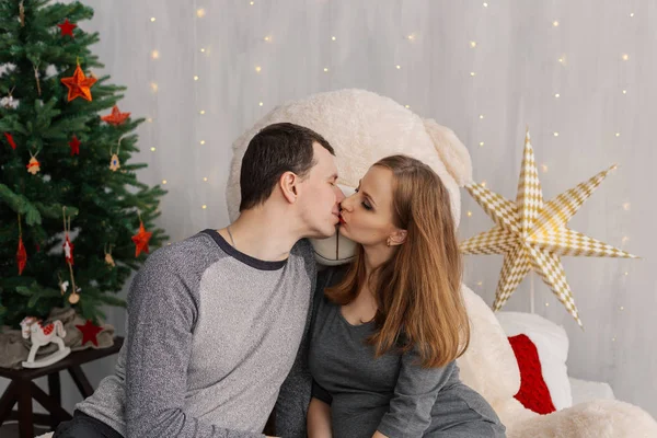 Velmi krásná dívka a muž na posteli s medvědem v místnosti vánoční. — Stock fotografie
