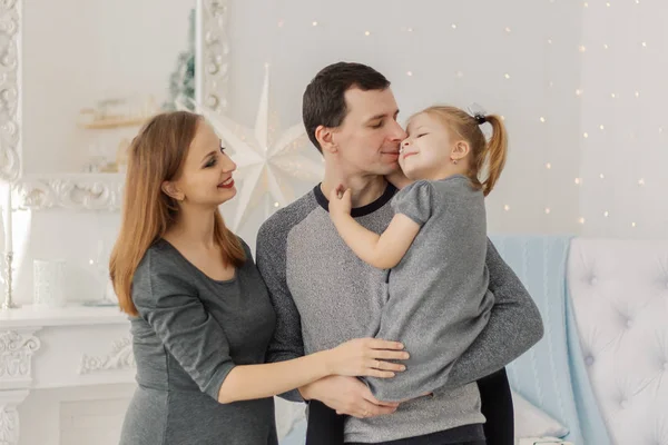 Happy and beautiful family of three at a festive bright New Year room . — стоковое фото