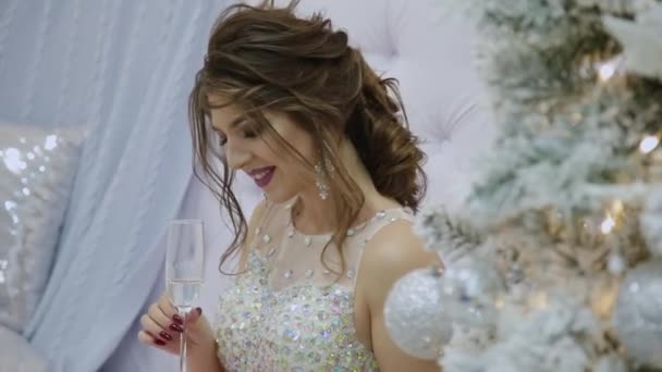 Très belle fille boit du champagne et s'assoit sur le canapé dans le décor du Nouvel An . — Video