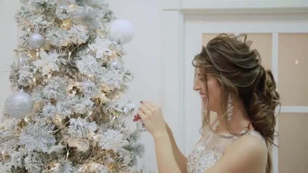 Heel mooi meisje versiert de kerstboom. — Stockvideo