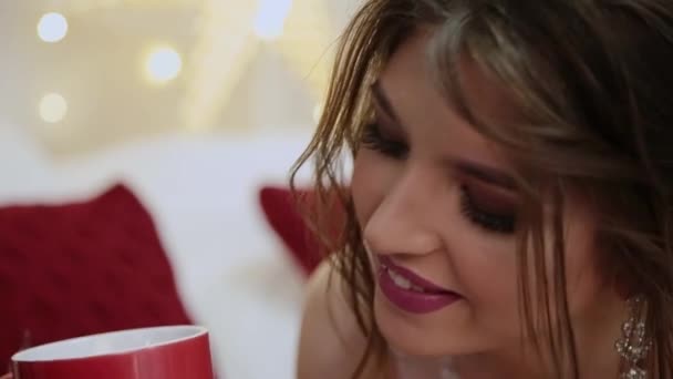 Sehr schönes Mädchen trinkt Tee auf dem Weihnachtsbett. — Stockvideo
