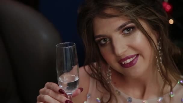 Mycket vacker flicka med ett glas champagne på nyår inredningen. — Stockvideo