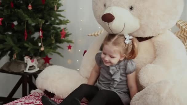 Menina pequena e muito bonita brincando com um urso anos novos . — Vídeo de Stock