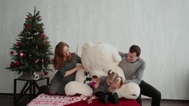 Веселая и красивая семья играет на кровати с медведем в новогоднем декоре . — стоковое видео