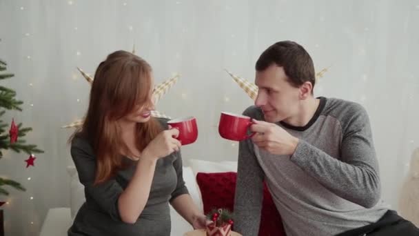 Chica embarazada y su marido en una cama en el estilo de Año Nuevo, Navidad 2019 . — Vídeos de Stock