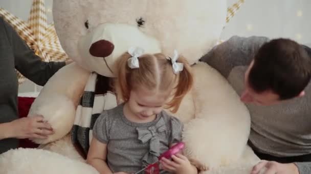 Veselá a krásná rodina hraje na posteli s medvědem v novoroční výzdoba. — Stock video
