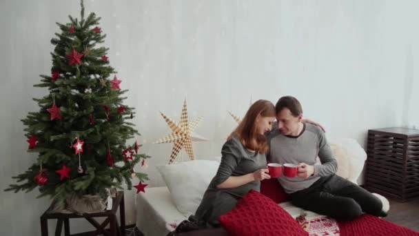 Έγκυος κορίτσι και ο σύζυγός της για ένα κρεβάτι σε στυλ νέο έτος, Χριστούγεννα 2019. — Αρχείο Βίντεο