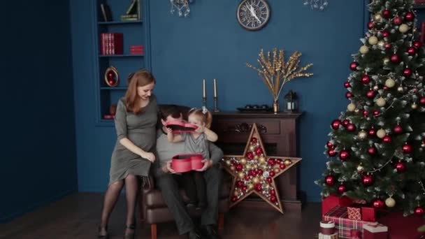 Uma família de três abre presentes de Ano Novo perto da lareira, Natal 2019 . — Vídeo de Stock