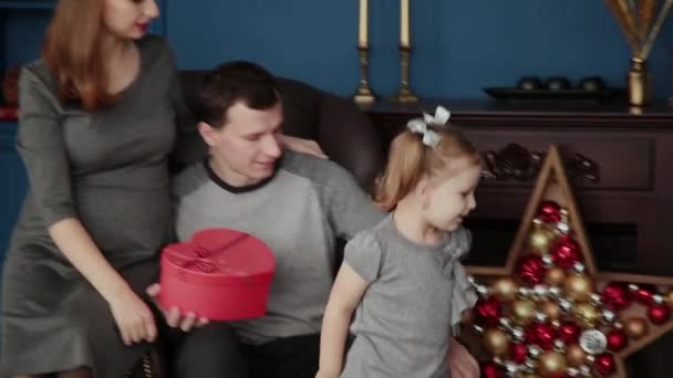 Семья из трех человек открывает новогодние подарки у камина, Рождество 2019 . — стоковое видео