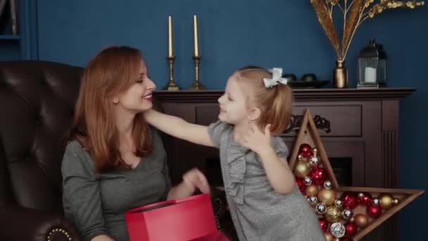 La niña abre un regalo de Año Nuevo con su madre, Navidad 2019 . — Vídeos de Stock