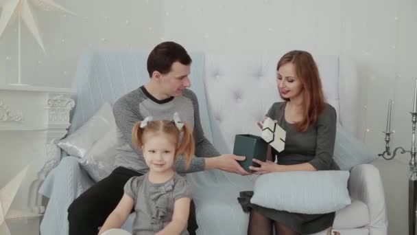 Una familia de tres personas sentadas en el sofá y hablando en Nochevieja, Navidad 2019 . — Vídeos de Stock