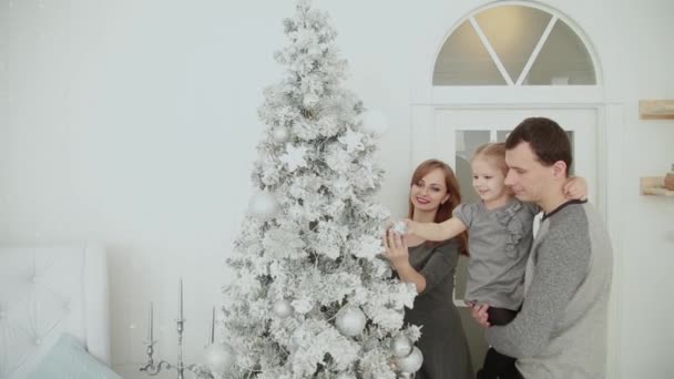 Сім'я стоїть біля ялинки, сміється з розмов та зворушливих іграшок, чекаючи Різдва. . — стокове відео