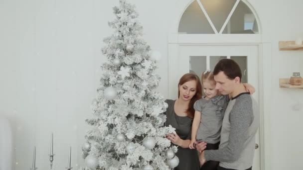 Сім'я стоїть біля ялинки, сміється з розмов та зворушливих іграшок, чекаючи Різдва. . — стокове відео
