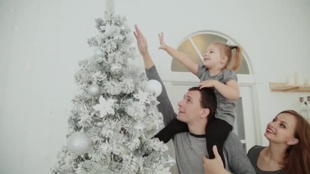 La familia está de pie cerca del árbol de Navidad, riendo hablando y tocando juguetes mientras espera la Navidad . — Vídeos de Stock