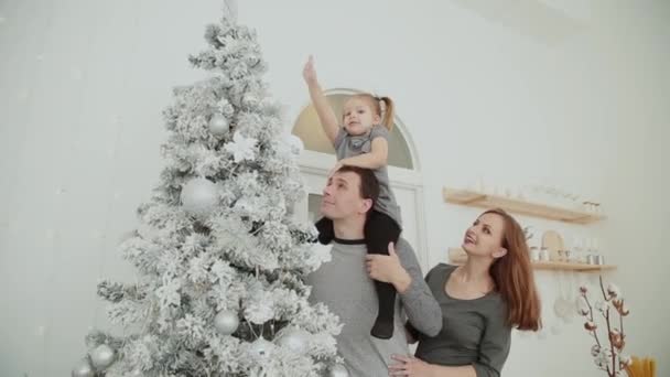 La familia está de pie cerca del árbol de Navidad, riendo hablando y tocando juguetes mientras espera la Navidad . — Vídeos de Stock