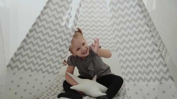 Very beautiful and little girl playing in a tepee. — Stock Video