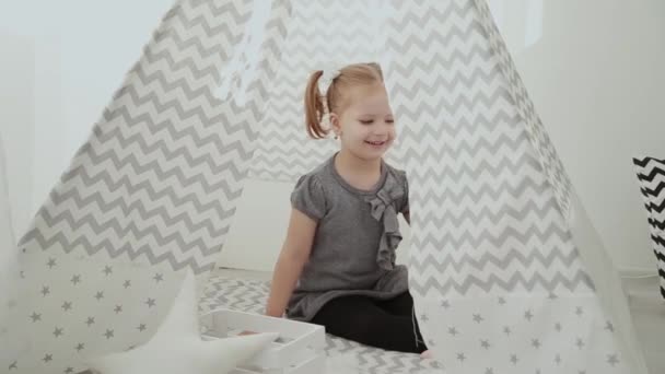 Very beautiful and little girl playing in a tepee. — Stock Video