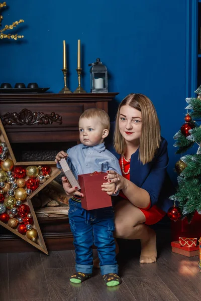 Porträt einer glücklichen Mutter und eines entzückenden Babys, die Weihnachten feiern. Neujahrsferien. Kleinkind mit Mama im festlich geschmückten Raum mit Christbaum und Dekoration. — Stockfoto