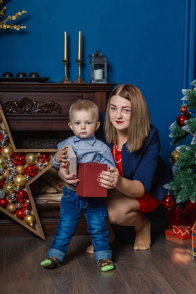 Porträt einer glücklichen Mutter und eines entzückenden Babys, die Weihnachten feiern. Neujahrsferien. Kleinkind mit Mama im festlich geschmückten Raum mit Christbaum und Dekoration. — Stockfoto