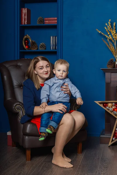 Porträt einer glücklichen Mutter und eines entzückenden Babys, die Weihnachten feiern. Neujahrsferien. Kleinkind mit Mama im festlich geschmückten Raum mit Christbaum und Dekoration. — Stockfoto