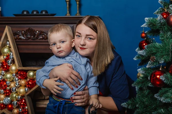 幸せな母とかわいい赤ちゃんの肖像画は、クリスマスを祝います。新しい年の休日。クリスマス ツリーとデコレーションでお祝いに飾られた部屋で母と幼児. — ストック写真