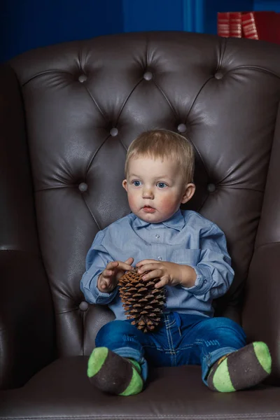 Маленький хлопчик сидить у старому шкіряному кріслі . — стокове фото