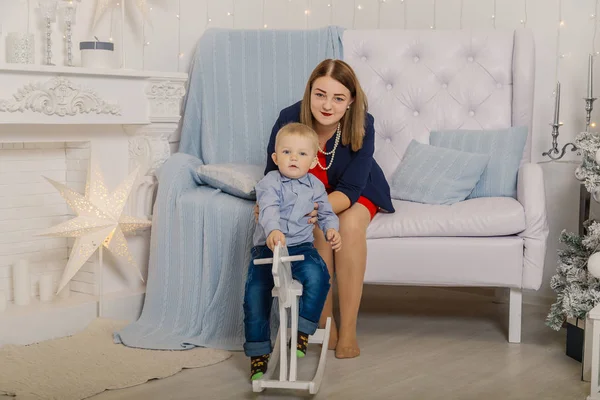 Porträt einer glücklichen Mutter und eines entzückenden Babys, die Weihnachten feiern. Neujahrsferien. Kleinkind mit Mama im festlich geschmückten Raum mit Christbaum und Dekoration. — Stockfoto