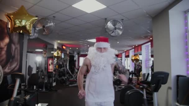 Instruktur kebugaran Santa Claus di gym berjalan di atas treadmill dan grimm . — Stok Video