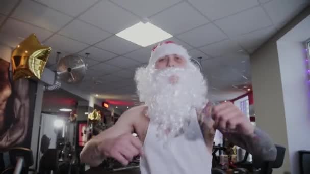 Fitness instruktor Santa Claus v tělocvičně běží na běžeckém pásu a grimasy. — Stock video