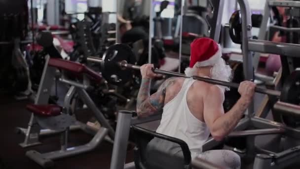 Fitness instruktor Santa Claus v tělocvičně u baru na dřepy. — Stock video